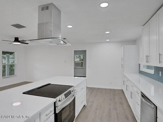 kitchen featuring light hardwood / wood-style floors, appliances with stainless steel finishes, ceiling fan, island range hood, and white cabinets