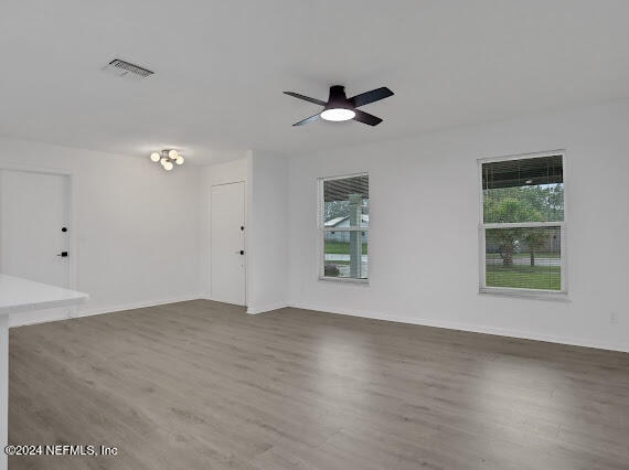 unfurnished room with plenty of natural light, ceiling fan, and dark hardwood / wood-style flooring