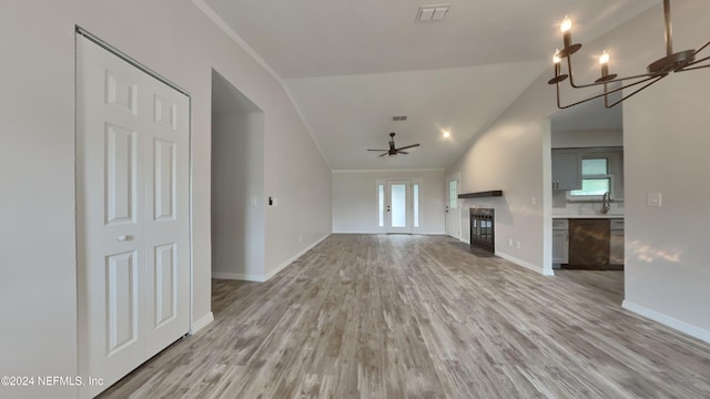 unfurnished living room featuring light hardwood / wood-style floors, sink, ornamental molding, ceiling fan with notable chandelier, and vaulted ceiling