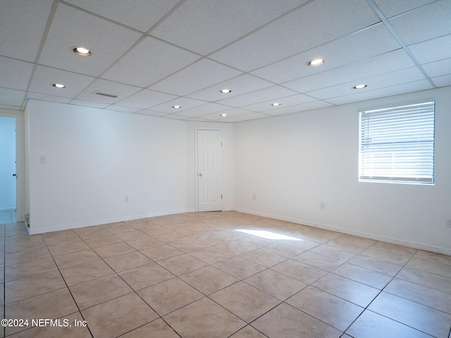 tiled empty room featuring a drop ceiling