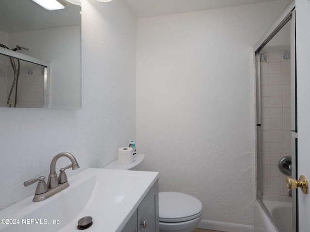 full bathroom featuring vanity, combined bath / shower with glass door, and toilet