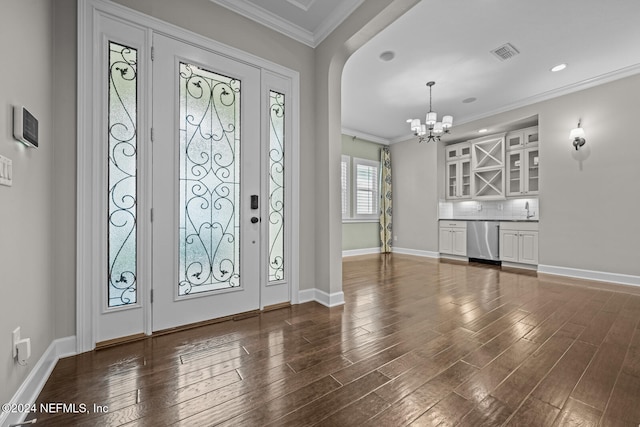 foyer entrance with a chandelier, dark hardwood / wood-style flooring, and ornamental molding