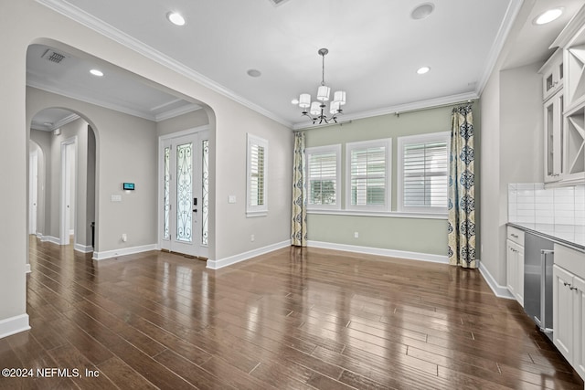 unfurnished dining area featuring dark hardwood / wood-style flooring, french doors, crown molding, and an inviting chandelier