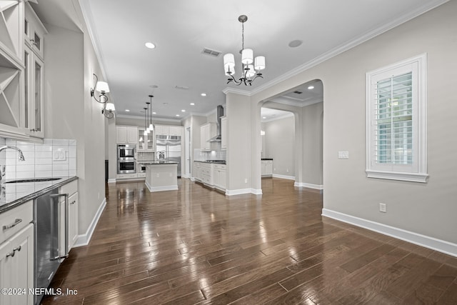 kitchen with backsplash, decorative light fixtures, white cabinetry, and sink