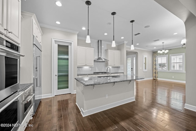 kitchen with white cabinets, dark hardwood / wood-style flooring, wall chimney range hood, and sink