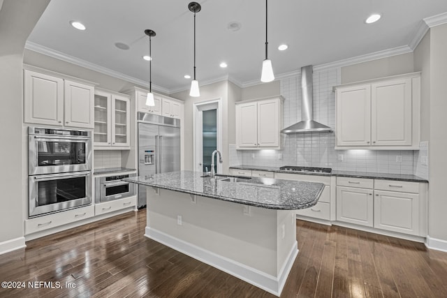 kitchen with white cabinets, sink, stainless steel appliances, and wall chimney range hood