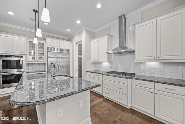 kitchen featuring an island with sink, dark wood-type flooring, wall chimney exhaust hood, and stainless steel appliances