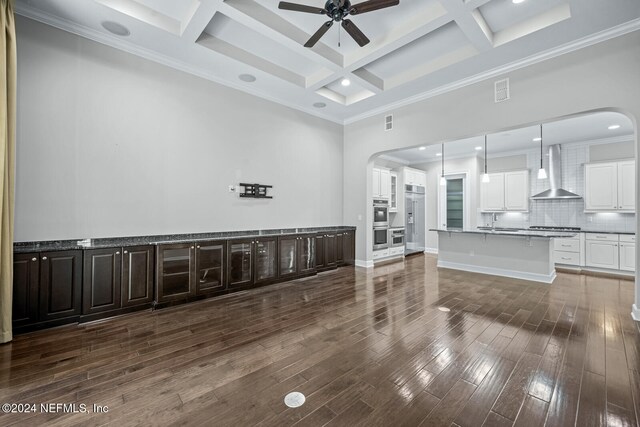 living room featuring dark wood-type flooring, coffered ceiling, crown molding, ceiling fan, and beam ceiling