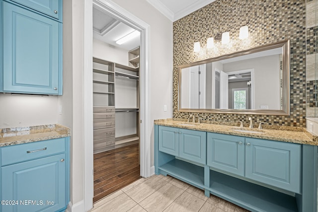 bathroom with vanity, wood-type flooring, backsplash, and crown molding