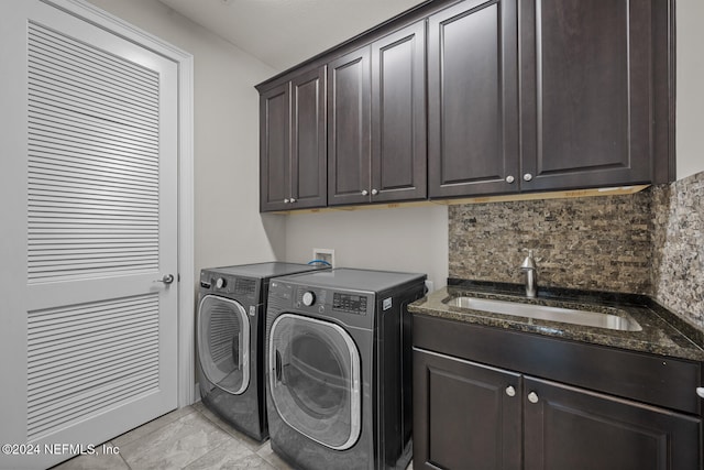 clothes washing area featuring cabinets, washing machine and clothes dryer, and sink