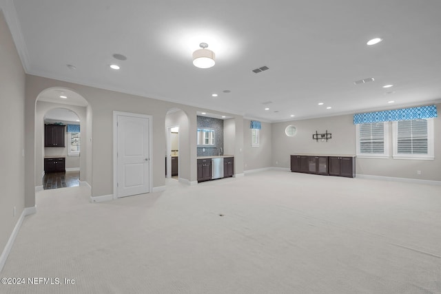 unfurnished living room featuring light colored carpet and ornamental molding