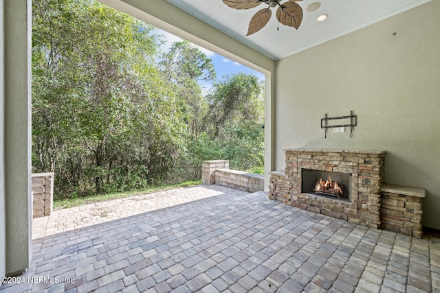 view of patio / terrace featuring ceiling fan and an outdoor stone fireplace