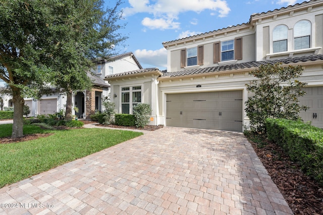 mediterranean / spanish house featuring a front yard and a garage