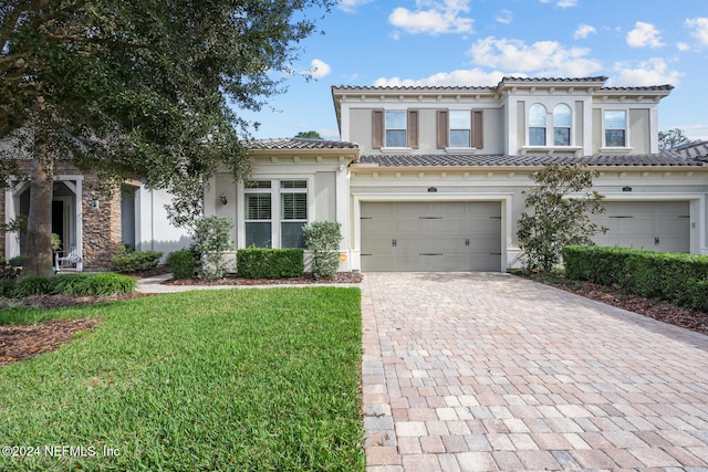 mediterranean / spanish-style home featuring a garage and a front lawn