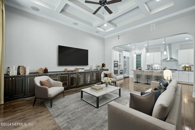 living room featuring a high ceiling, coffered ceiling, ornamental molding, beamed ceiling, and wood-type flooring