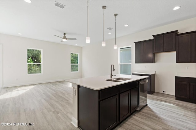 kitchen featuring light wood-type flooring, pendant lighting, sink, an island with sink, and dishwasher