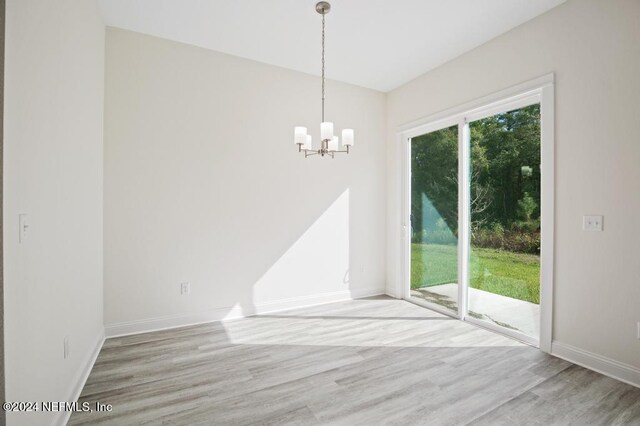 unfurnished dining area featuring an inviting chandelier and wood-type flooring