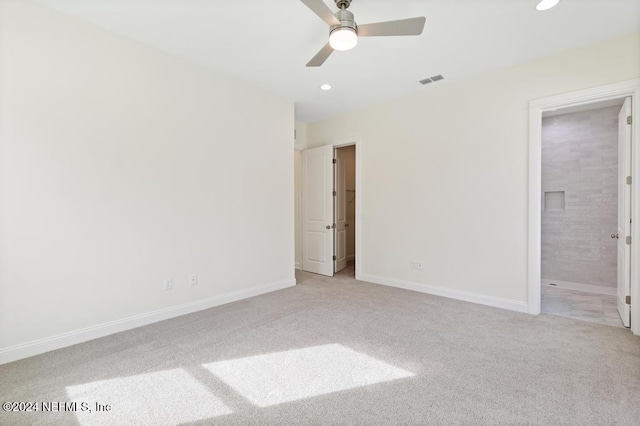 unfurnished bedroom featuring ensuite bath, light carpet, and ceiling fan