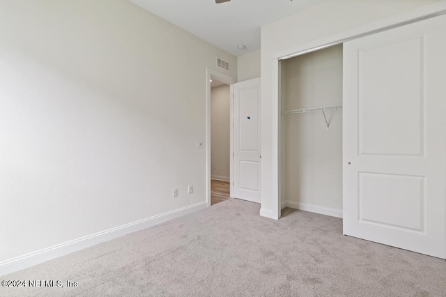 unfurnished bedroom featuring a closet and light colored carpet