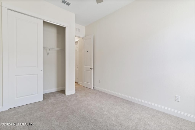 unfurnished bedroom featuring a closet and light carpet