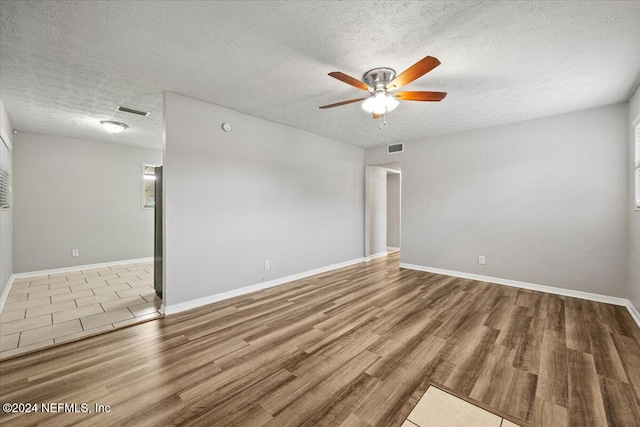 empty room featuring ceiling fan, wood-type flooring, and a textured ceiling