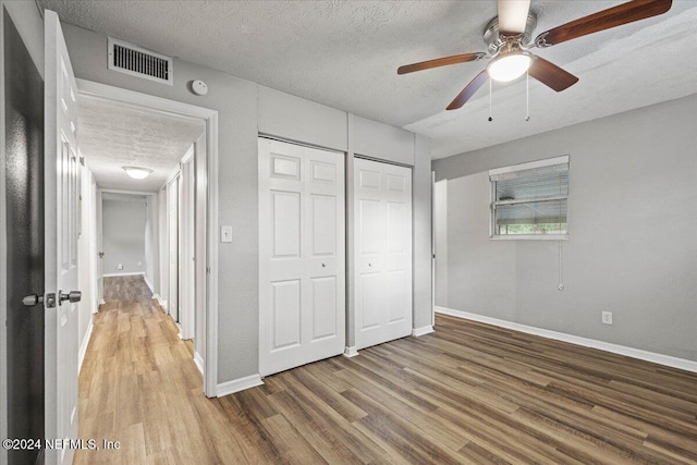 unfurnished bedroom with ceiling fan, a closet, a textured ceiling, and hardwood / wood-style flooring