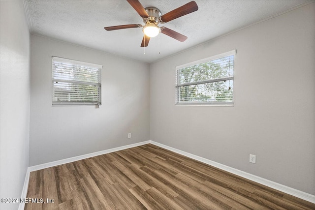 spare room featuring a healthy amount of sunlight, wood-type flooring, and a textured ceiling