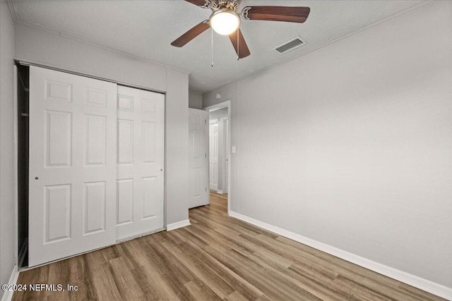 unfurnished bedroom with a textured ceiling, light wood-type flooring, a closet, and ceiling fan