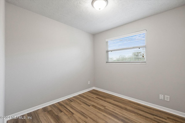 empty room featuring a textured ceiling and dark hardwood / wood-style flooring