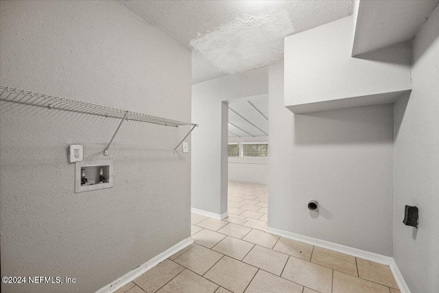 clothes washing area with hookup for a washing machine, light tile patterned flooring, a textured ceiling, and hookup for an electric dryer