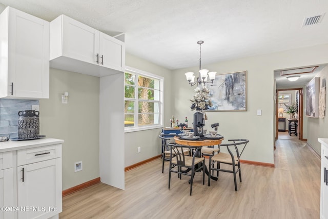 dining area with an inviting chandelier and light hardwood / wood-style flooring