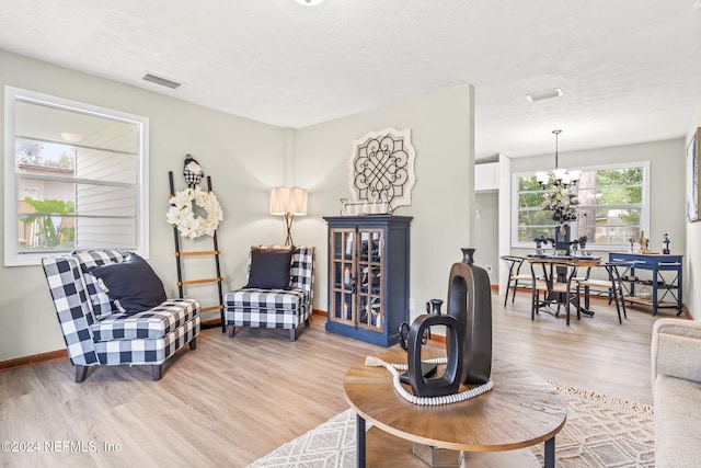 living room featuring a textured ceiling, light wood-type flooring, and a notable chandelier