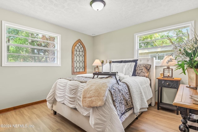 bedroom with a textured ceiling and light hardwood / wood-style flooring