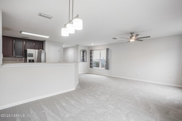 kitchen with dark brown cabinetry, decorative light fixtures, light colored carpet, stainless steel fridge, and ceiling fan