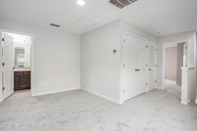 unfurnished bedroom with sink, ensuite bath, and light colored carpet