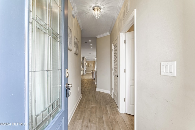 corridor with light hardwood / wood-style flooring, a chandelier, and crown molding