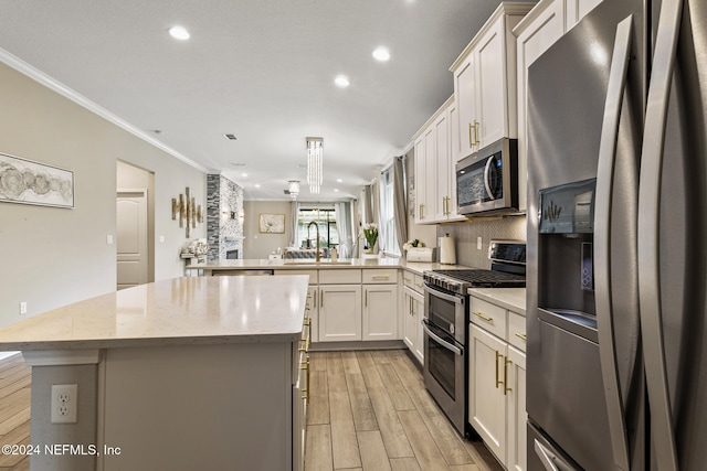 kitchen featuring crown molding, stainless steel appliances, sink, light hardwood / wood-style floors, and kitchen peninsula