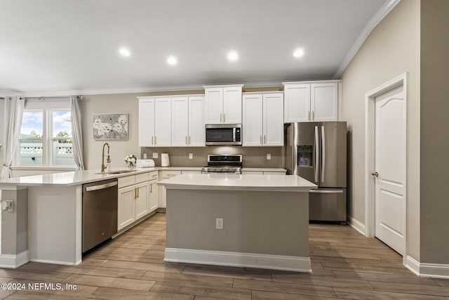 kitchen featuring crown molding, stainless steel appliances, wood-type flooring, and a kitchen island