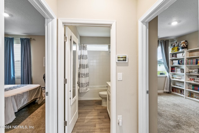 bathroom with shower / tub combo with curtain, a wealth of natural light, hardwood / wood-style floors, and a textured ceiling