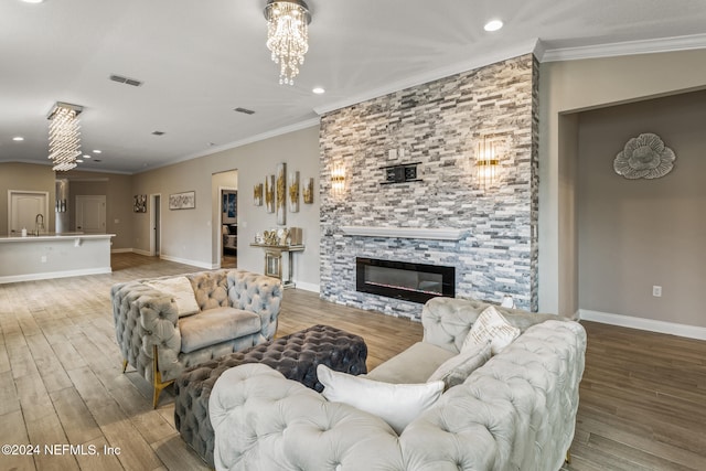 living room featuring sink, wood-type flooring, a stone fireplace, and crown molding