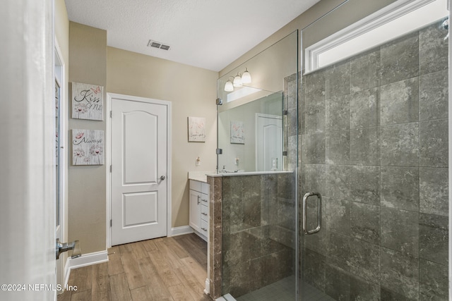 bathroom with hardwood / wood-style floors, vanity, an enclosed shower, and a textured ceiling