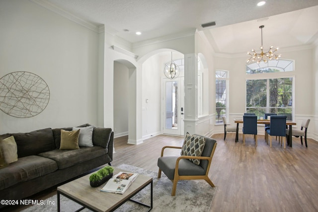 living room featuring wood-type flooring, a notable chandelier, crown molding, and a textured ceiling