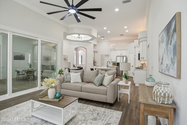 living room with sink, ceiling fan with notable chandelier, dark hardwood / wood-style floors, and crown molding