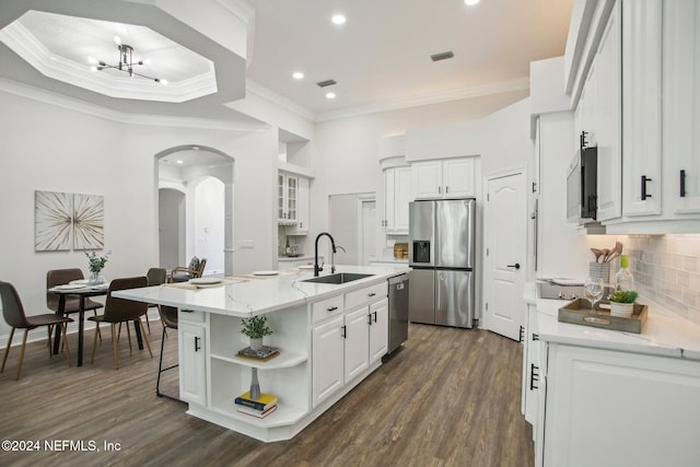 kitchen with stainless steel appliances, white cabinetry, dark hardwood / wood-style flooring, sink, and a kitchen island with sink