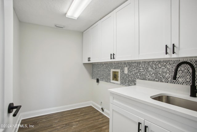 laundry room featuring cabinets, sink, washer hookup, a textured ceiling, and dark wood-type flooring