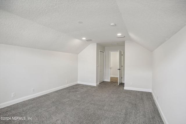 bonus room with a textured ceiling, vaulted ceiling, and carpet