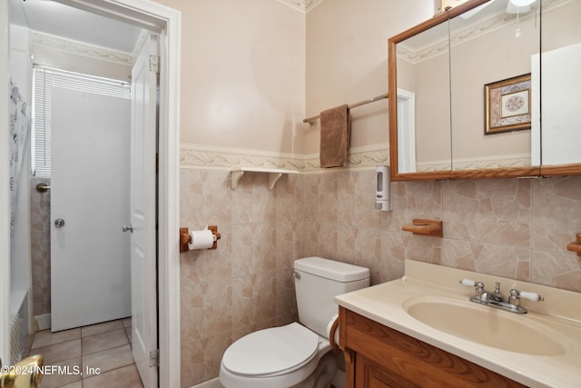 bathroom with tile walls, toilet, vanity, and tile patterned floors