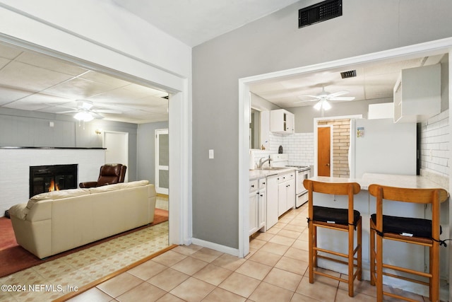 kitchen with white cabinets, light tile patterned floors, white appliances, and backsplash