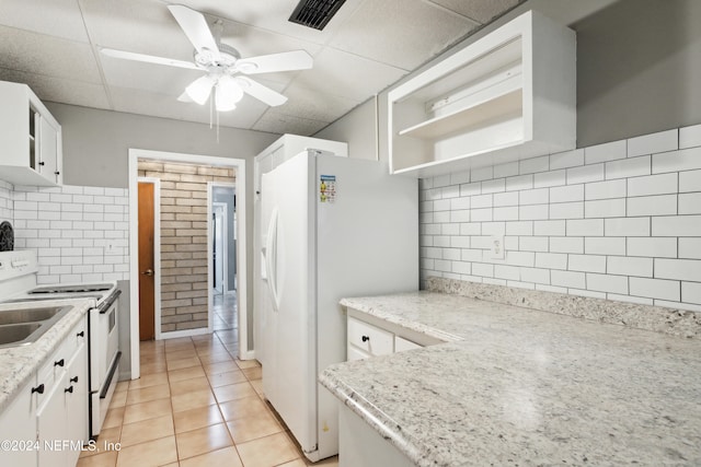 kitchen featuring white cabinetry, a paneled ceiling, light tile patterned flooring, and white appliances