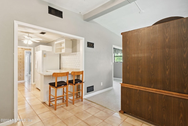 kitchen with a kitchen breakfast bar, light tile patterned floors, ceiling fan, and beam ceiling